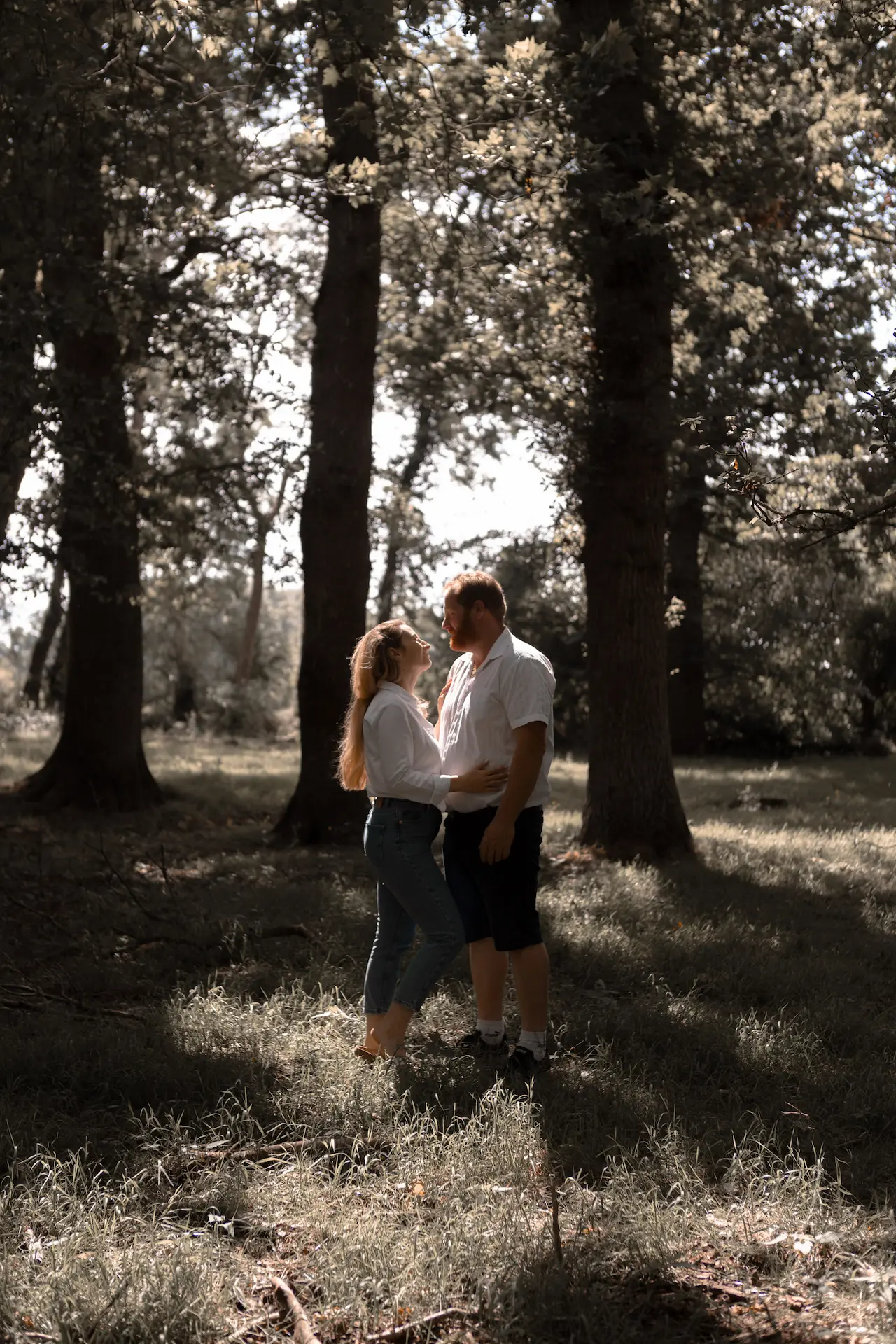 séance d'engagement en normandie dans une forêt couple se regardant et bercé dans une lumière chaleureuse